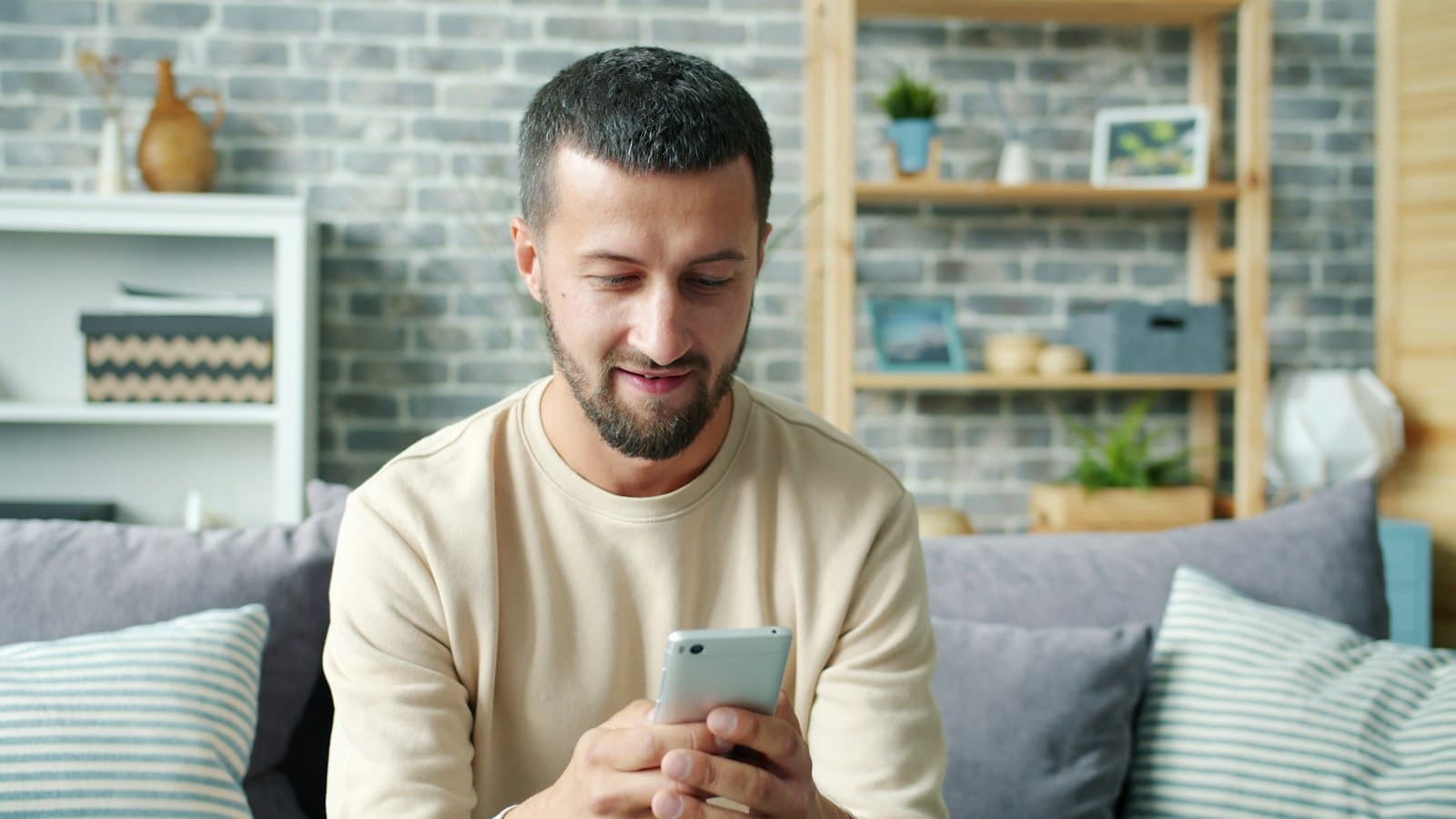 A man on a sofa reading a conversation on his smartphone